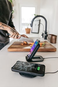 phones with ZAGG accessories charging while person cooks