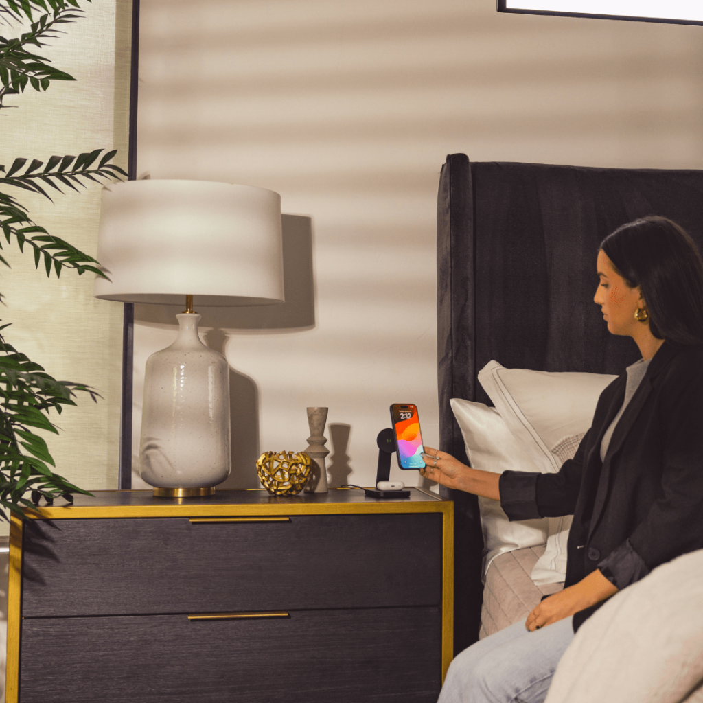 woman sitting on the edge of her bed plugging her phone in